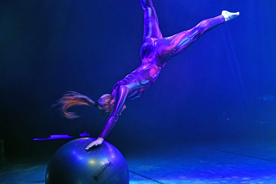 Artist Monique Schröder pushes herself off a Pezziball and stretches her legs in the air