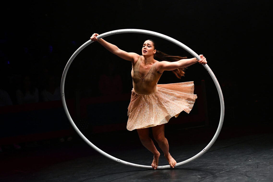Artistin Yahav Adar steht mit wehendem Kleid in einem weißen Cyr Wheel