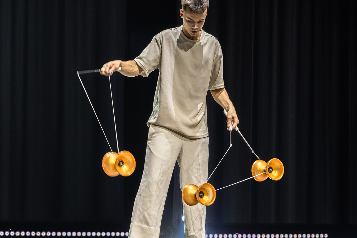 Ein junger Artist der Diabolo-Kunst zeigt vollen Einsatz und konzentriert sich ganz auf sein Requisit, während er die Hände voll zu tun hat
