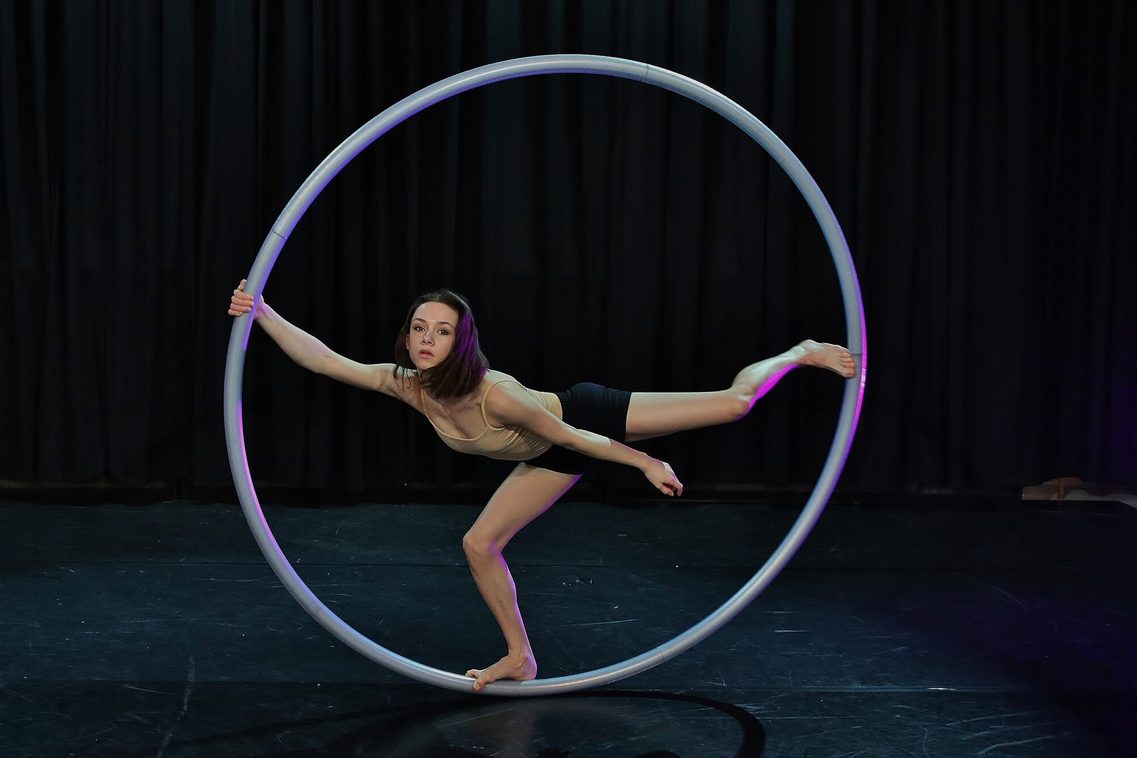 Eine junge Frau balanciert anmutig auf einem Bein im Cyr Wheel – ein wunderschöner Moment dieser faszinierenden Kunst