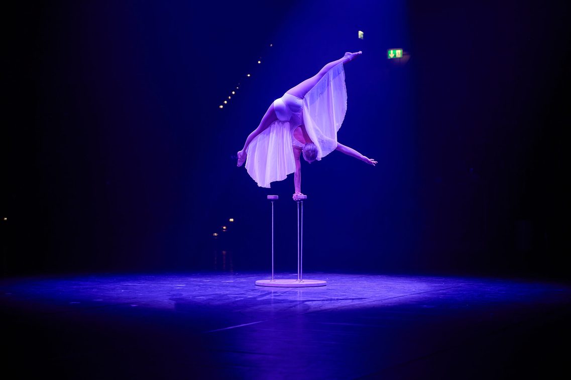 Eine junge Artistin zeigt ihr Können in der Equilibristik und balanciert in einem perfekten Handstand auf einem Requisit.