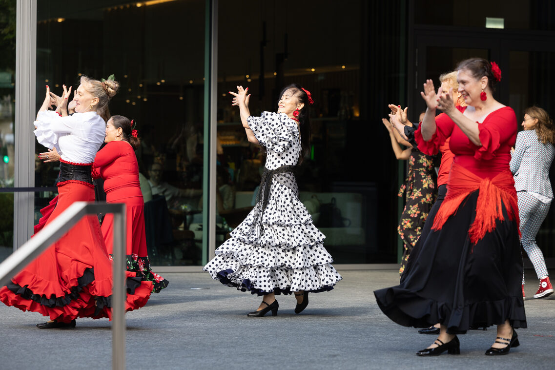 Mehrere Frauen in Flamencokostümen tanzen auf einer Terrasse.