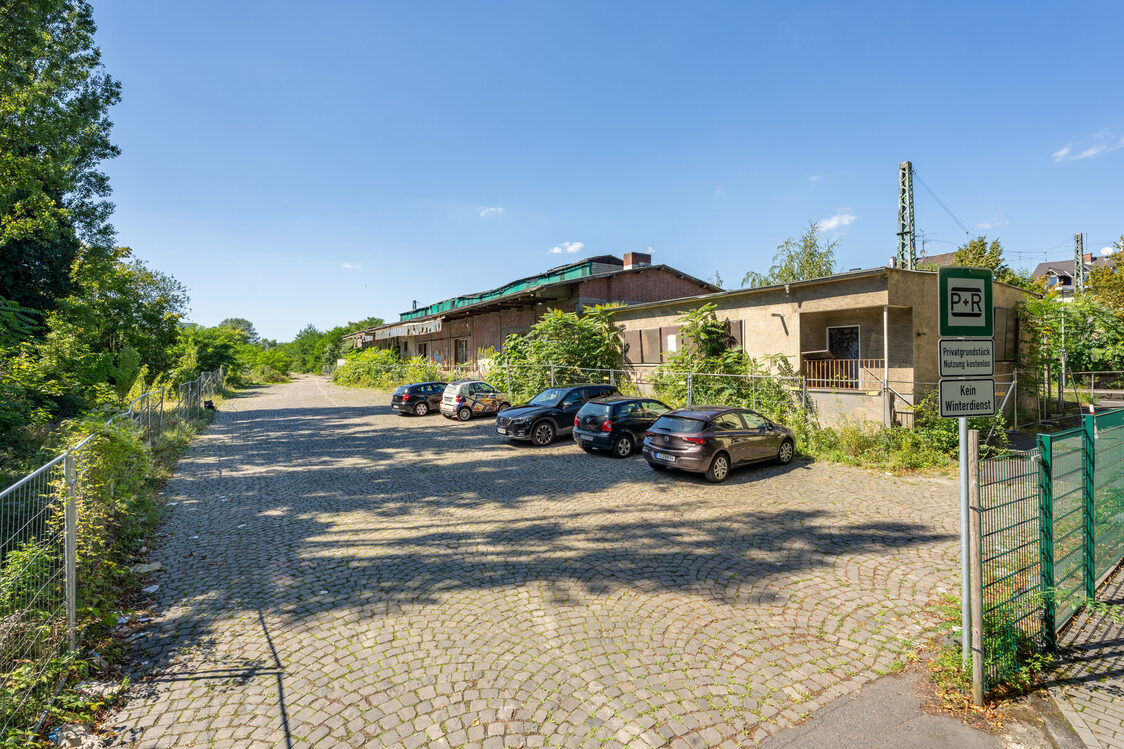 Cars park in front of the dilapidated goods shed.
