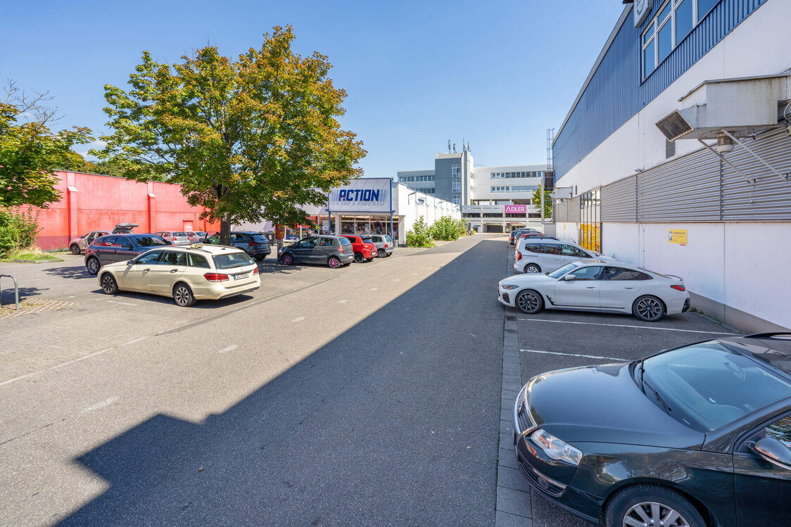 Cars are parked in large spaces in front of various stores.