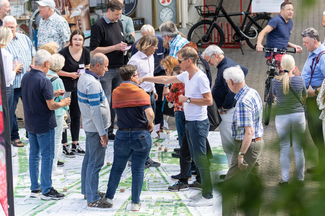 Eine Gruppe Männer und Frauen steht auf einem großen Plakat und diskutiert.