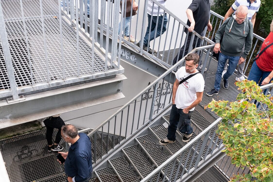 Grupa mężczyzn i kobiet schodzi po stalowych schodach.