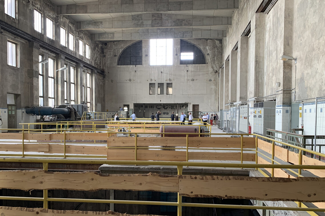 Eine Menschengruppe besichtigt eine lichtdurchflutete alte Fabrikhalle.