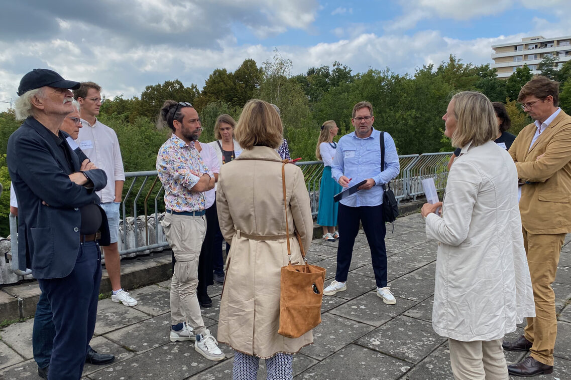 Menschen diskutieren auf einer verfallenen weitläufigen Terrasse mit einander.