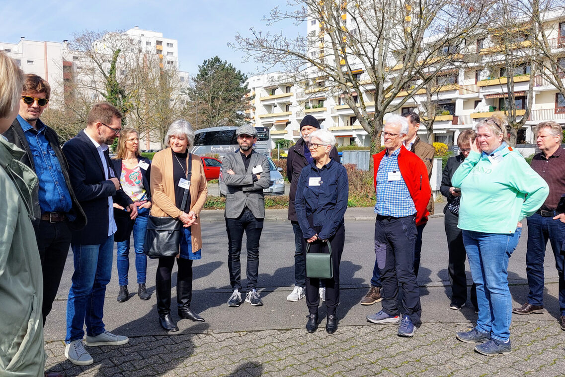 Eine Menschengruppe besichtigt eine Wohnsiedlung.