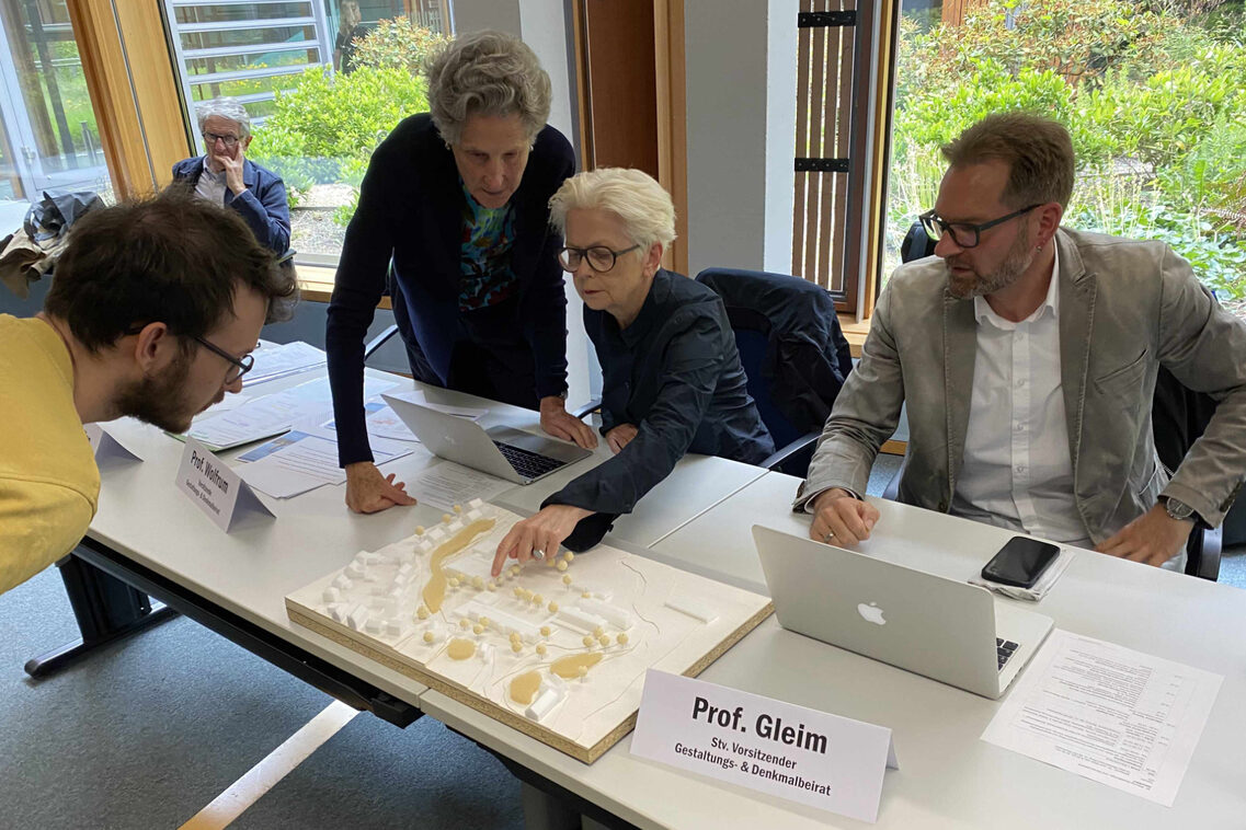 Menschen schauen ein städtebauliches Modell an.