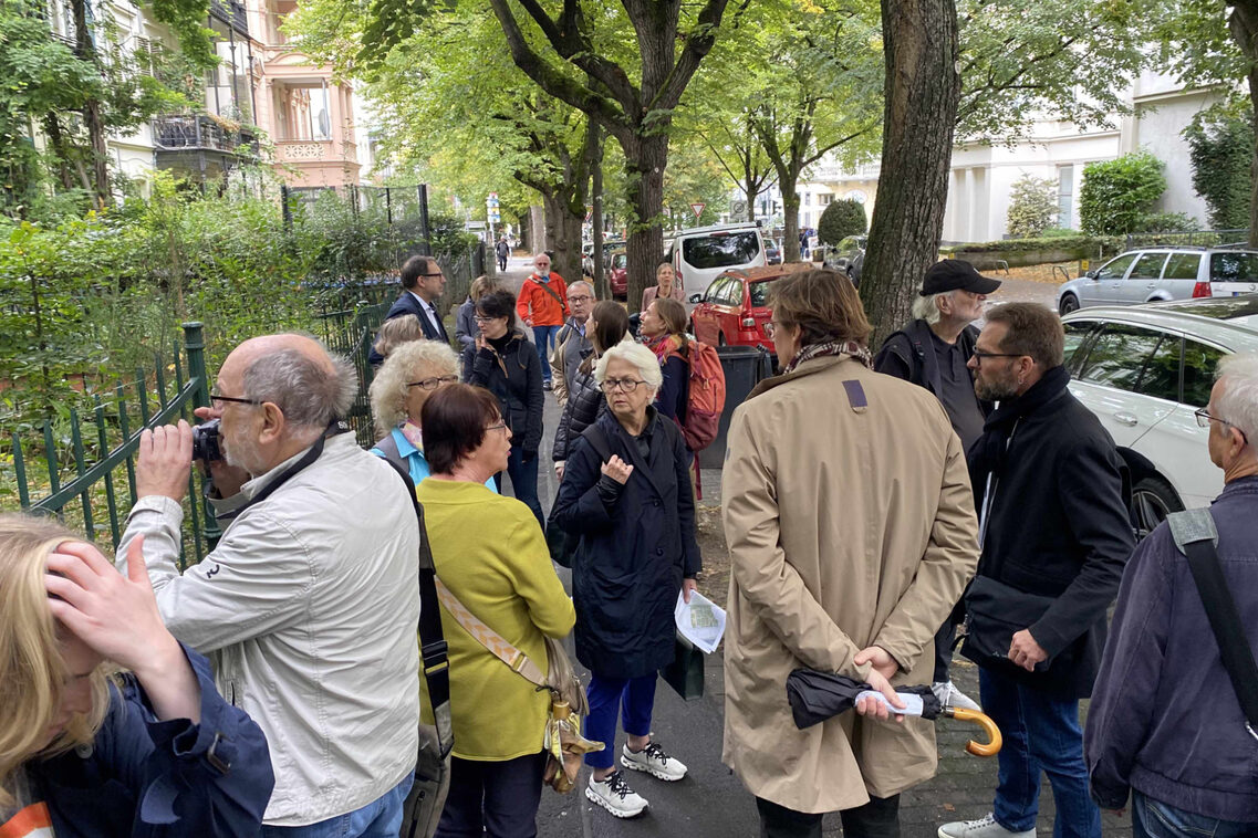 Eine Menschengruppe besichtigt historisch wertvolle Vorgärten der Gründerzeit.