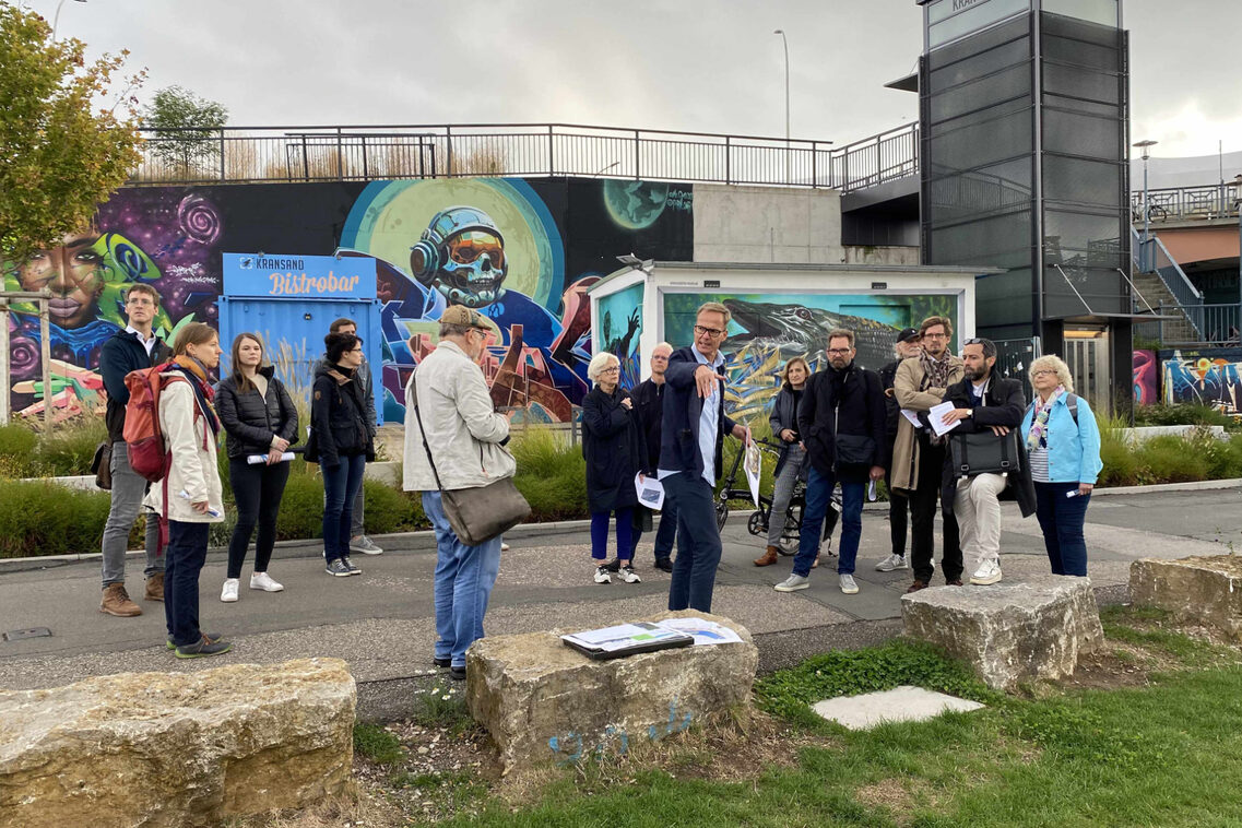 Eine Menschengruppe besichtigt einen konsumfreien Bereich am Rheinufer.