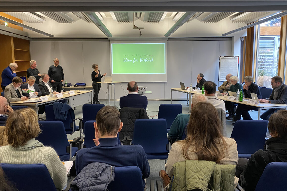 Eine Frau präsentiert Beirat und Publikum in der Sitzung ein Konzept.