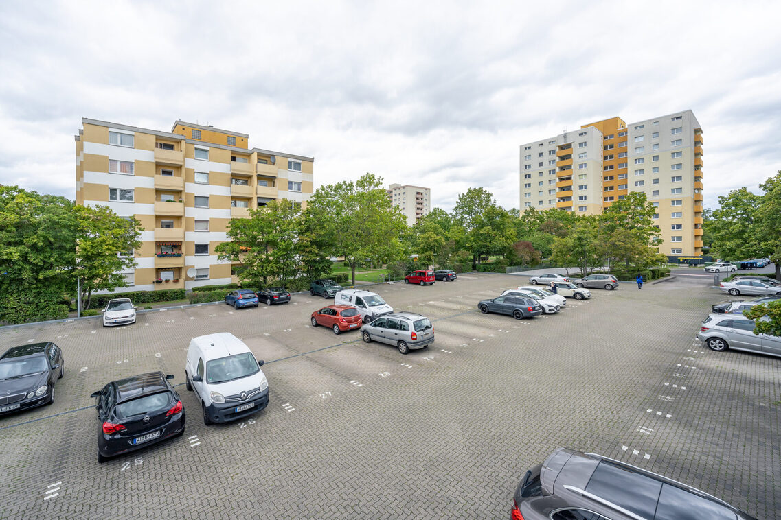 Parkende Autos auf einem Parkdeck umgeben von Hochhäusern und Zeilenbebauung