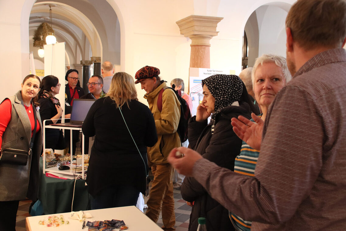 Mehrere Personen stehen gemischt und z.T. in Gespräche vertieft.