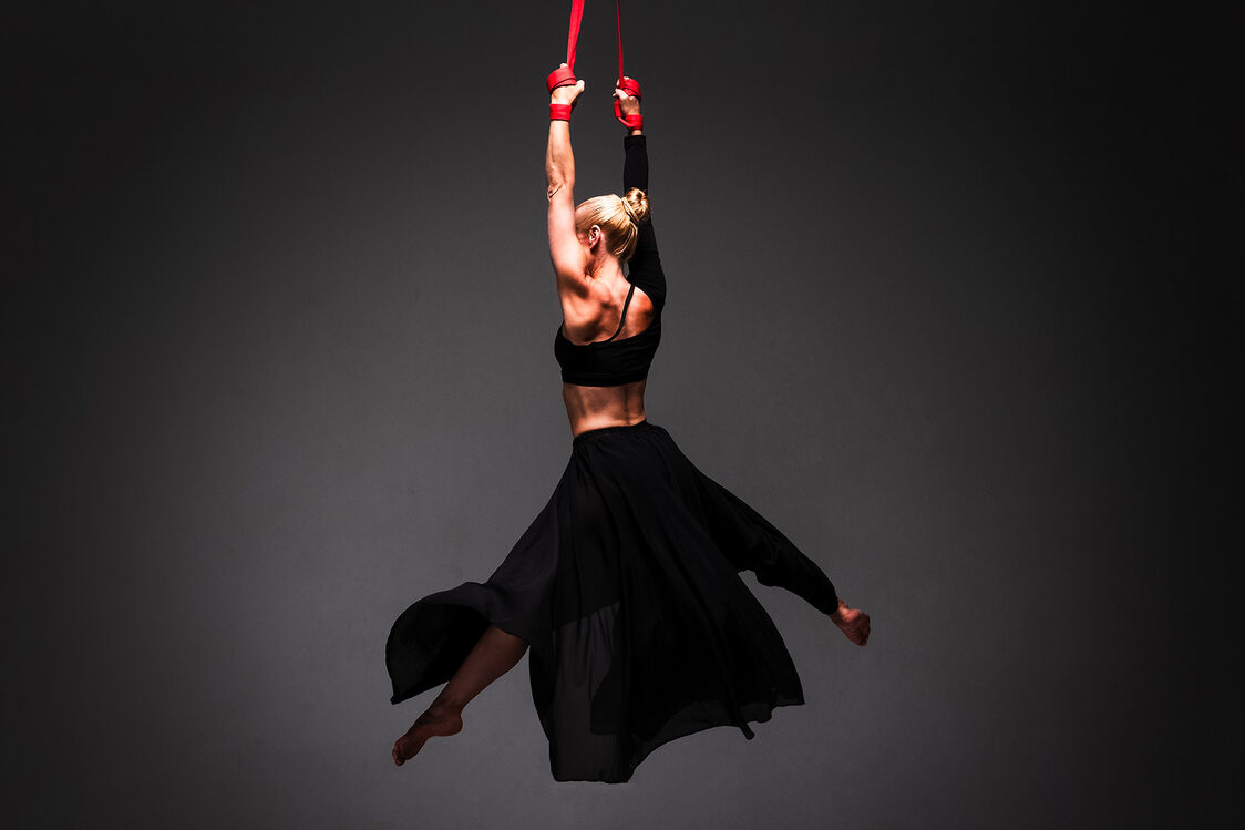 Woman hangs on two ropes in the air and does artistic exercises.