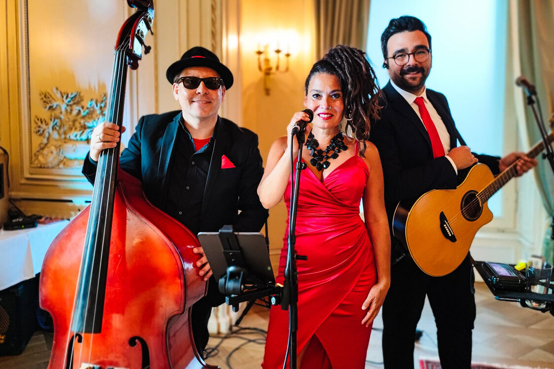 A singer on the mic with two musicians with double bass and guitar