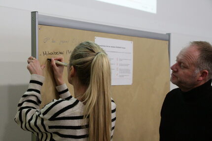 Frau schreibt an eine Pinnwand