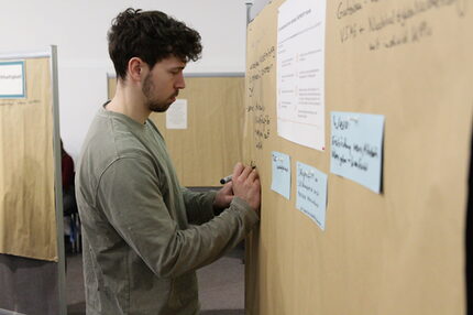 Mann schreibt auf eine Pinnwand