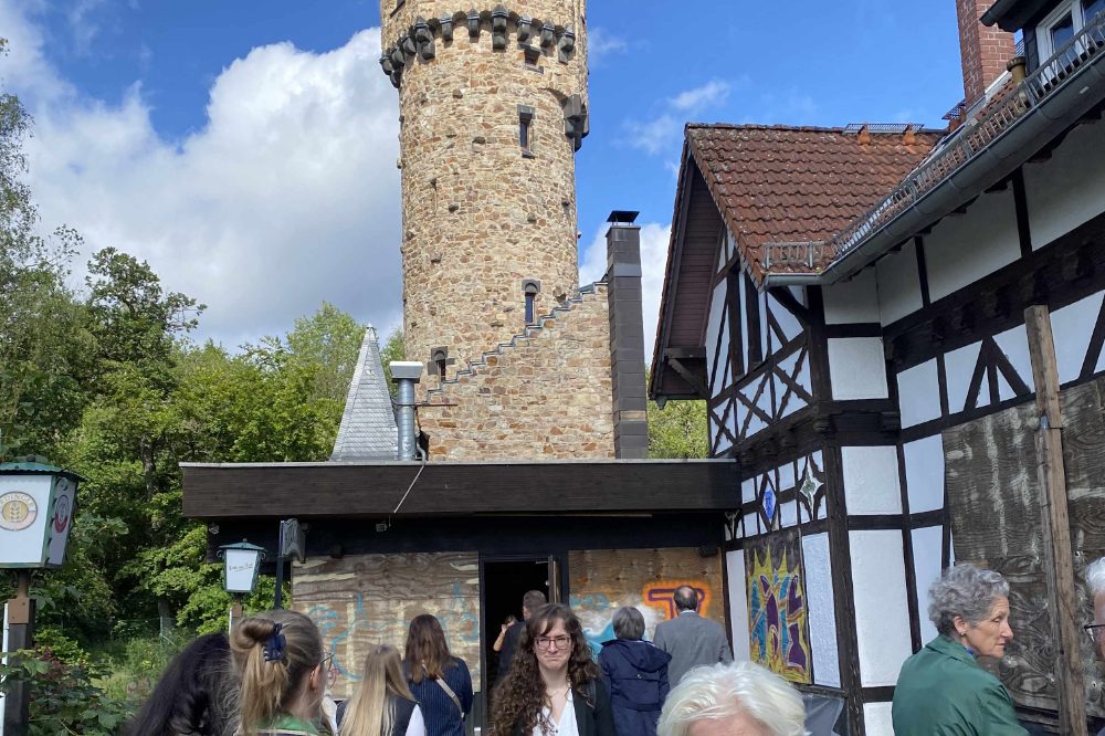 Eine Menschengruppe besichtigt das Außengelände eines historischen Turms.