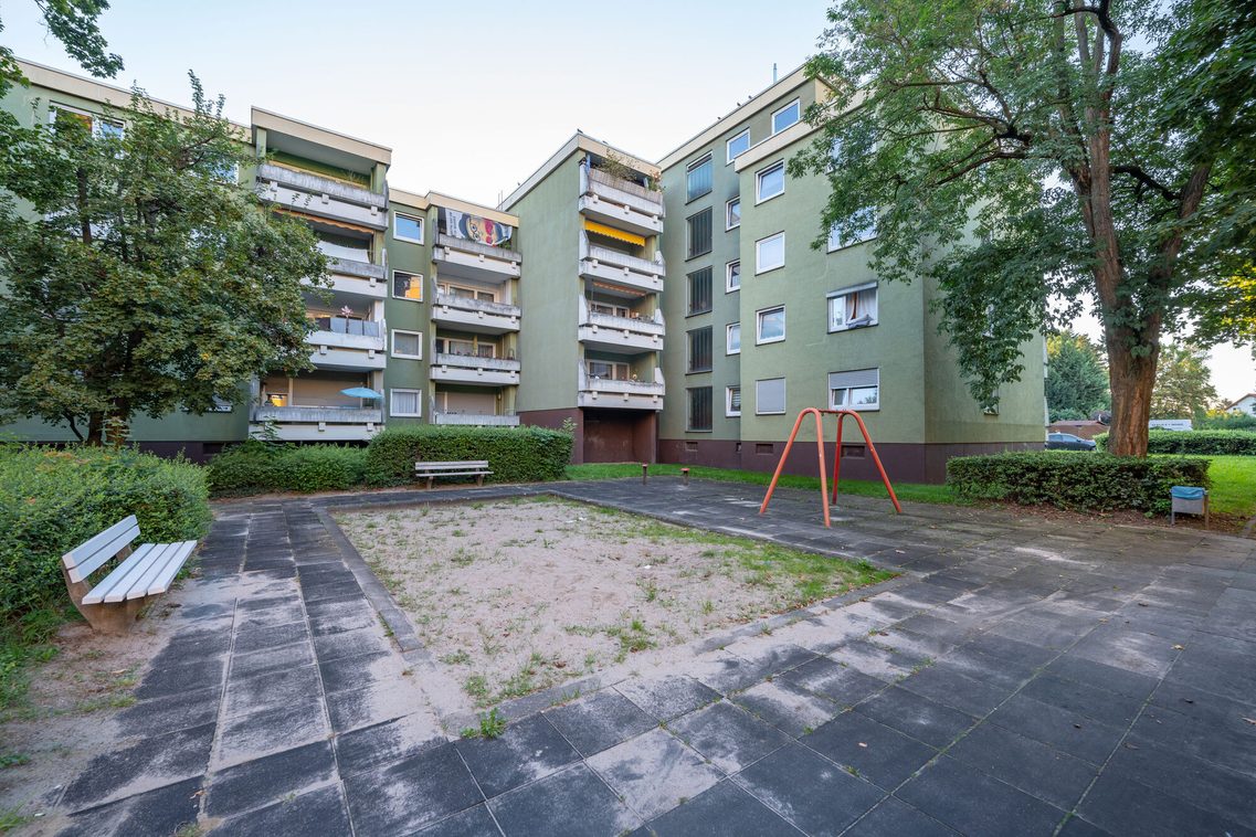 Spielplatz hinter einem Haus mit einem Sandkasten, einer Schaukel und zwei Bänken