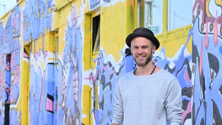 Uomo davanti a un grande edificio con graffiti