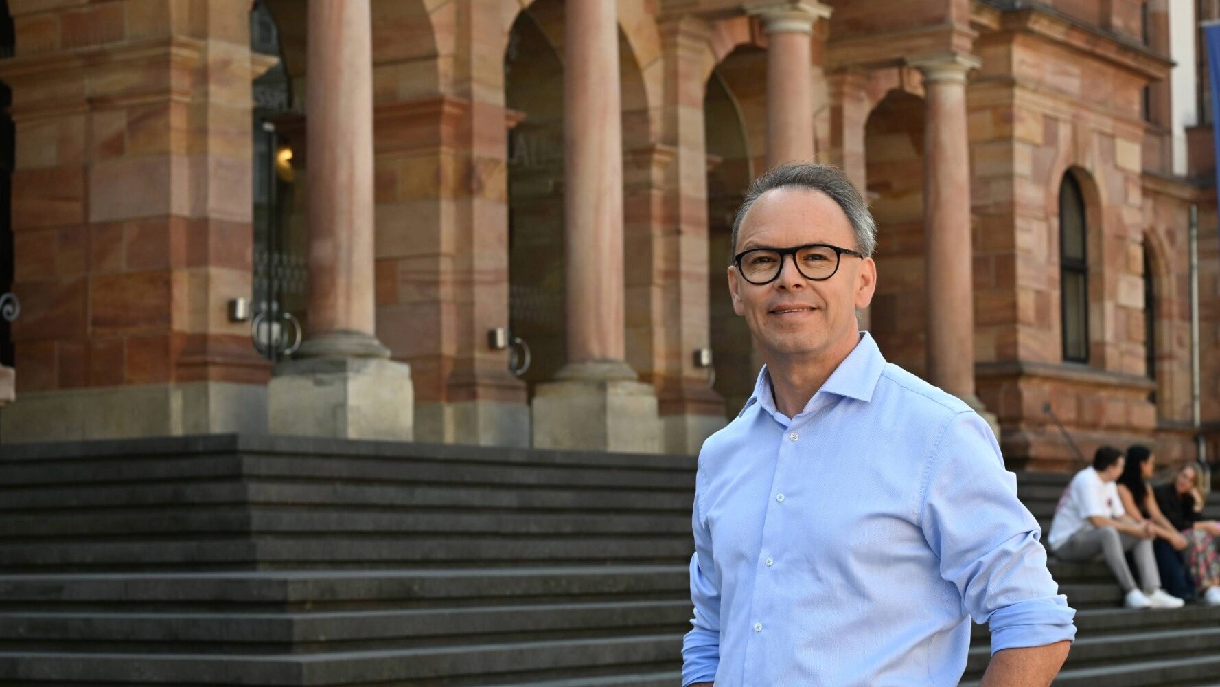 Mann mit kurzen Haaren vor historischem Gebäude