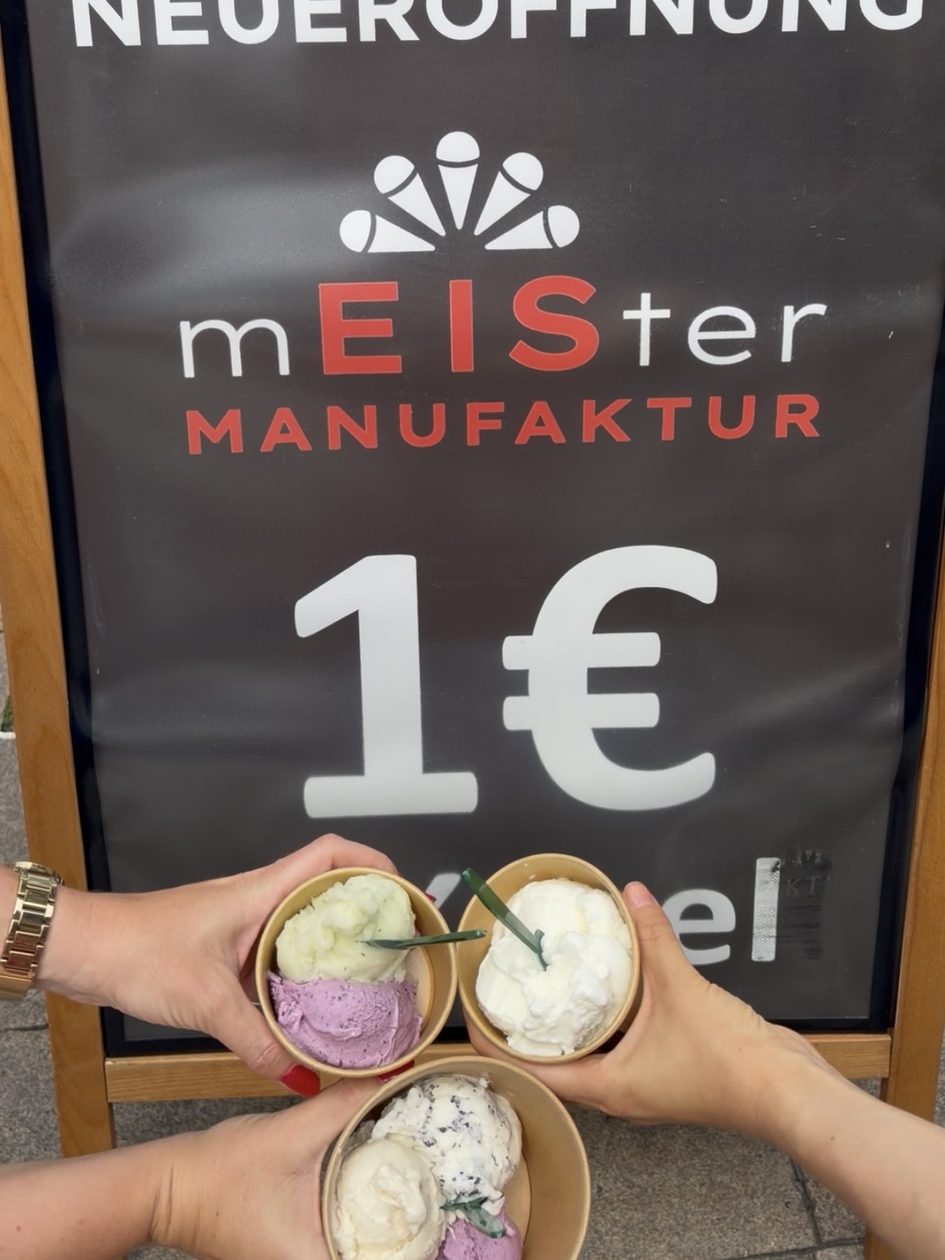 Hände mit Becher Eis in der Hand vor Plakat
