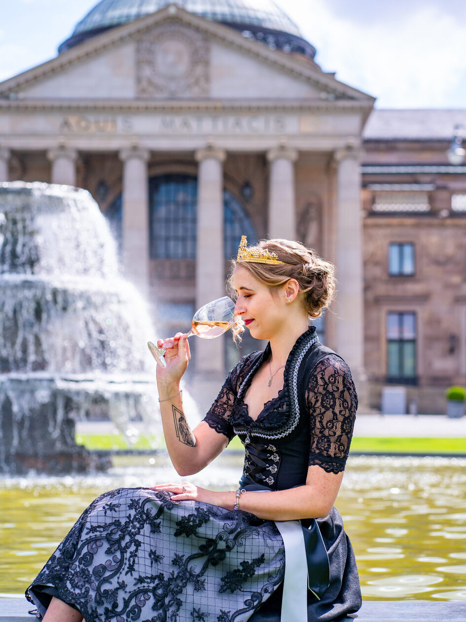 Annkathrin Dötsch in a dirndl and wine glass in front of the Kurhaus