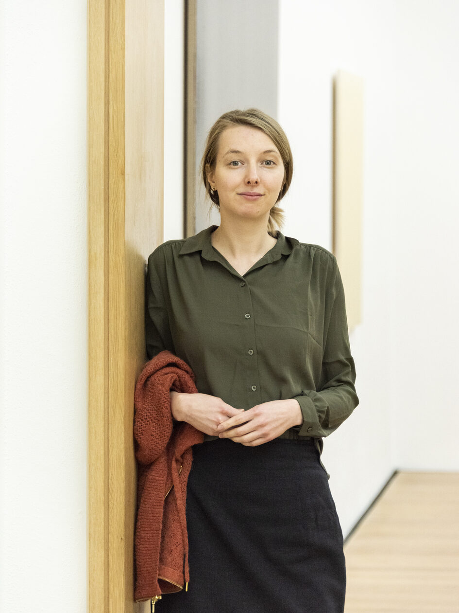 Junge blonde Frau, an Wand gelehnt