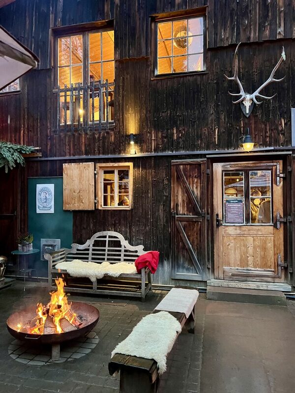 Holzfassade, Feuer, Bank mit Fellen