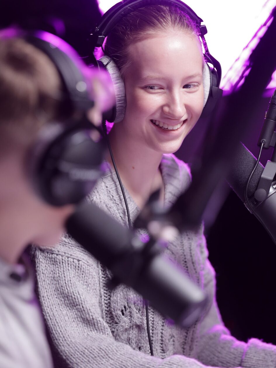 Mädchen mit Kopfhörern vor Podcast-Mikrofon