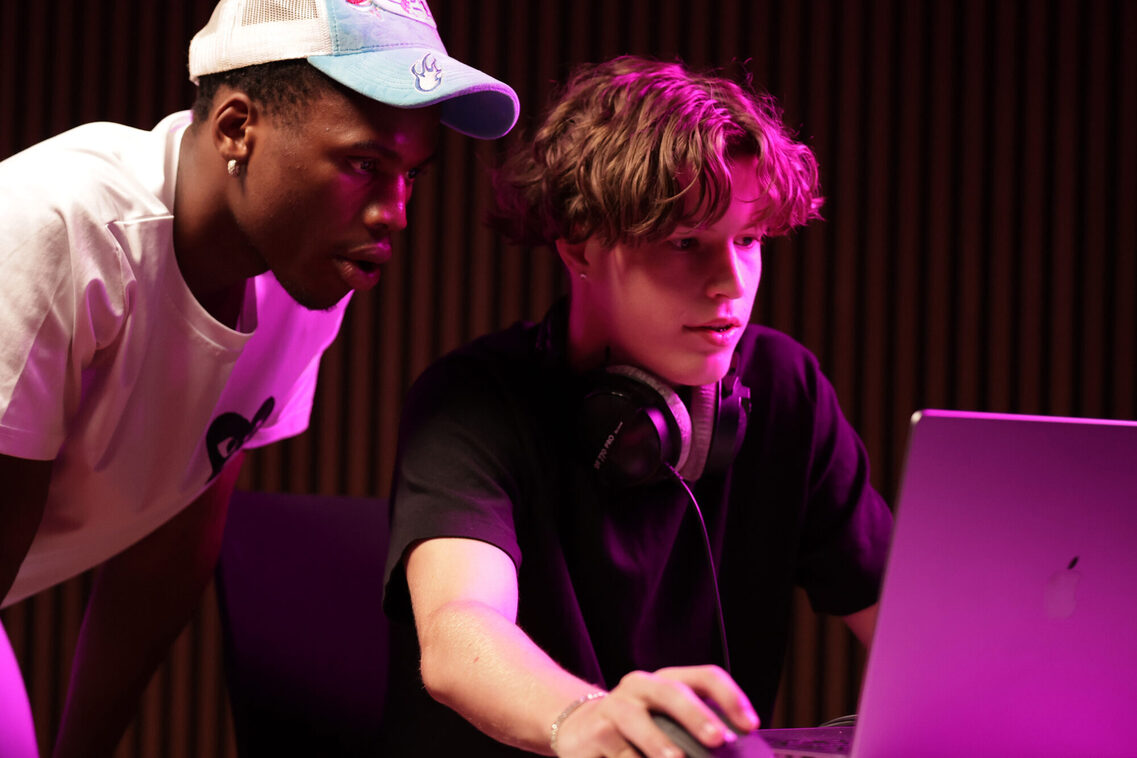 Jugendliche im Studio, wie sie vor einem Macbook sitzen