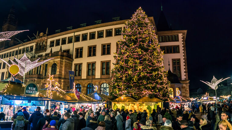 Geschmückter Tannenbaum mit Menschen davor