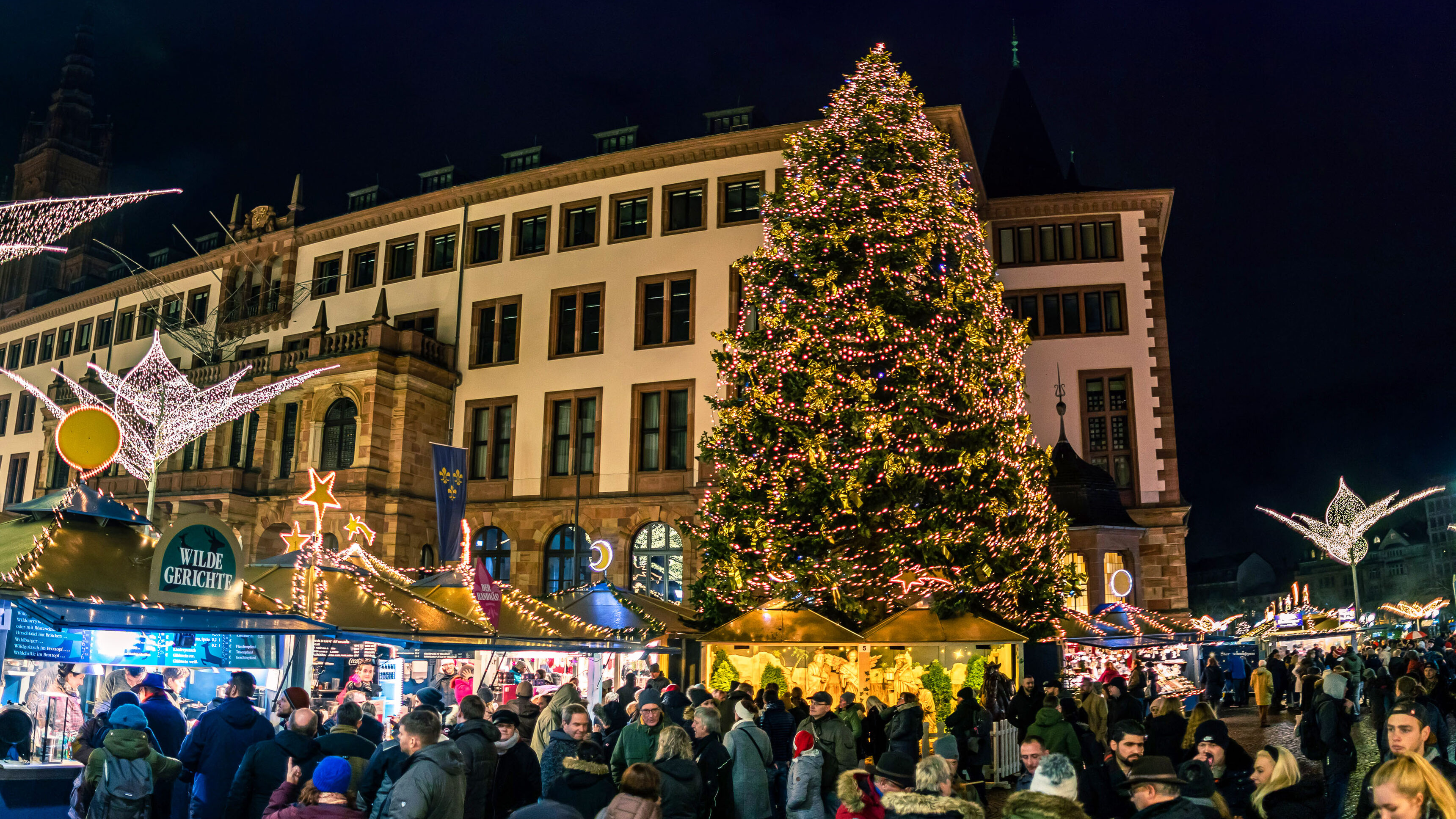 Geschmückter Tannenbaum mit Menschen davor