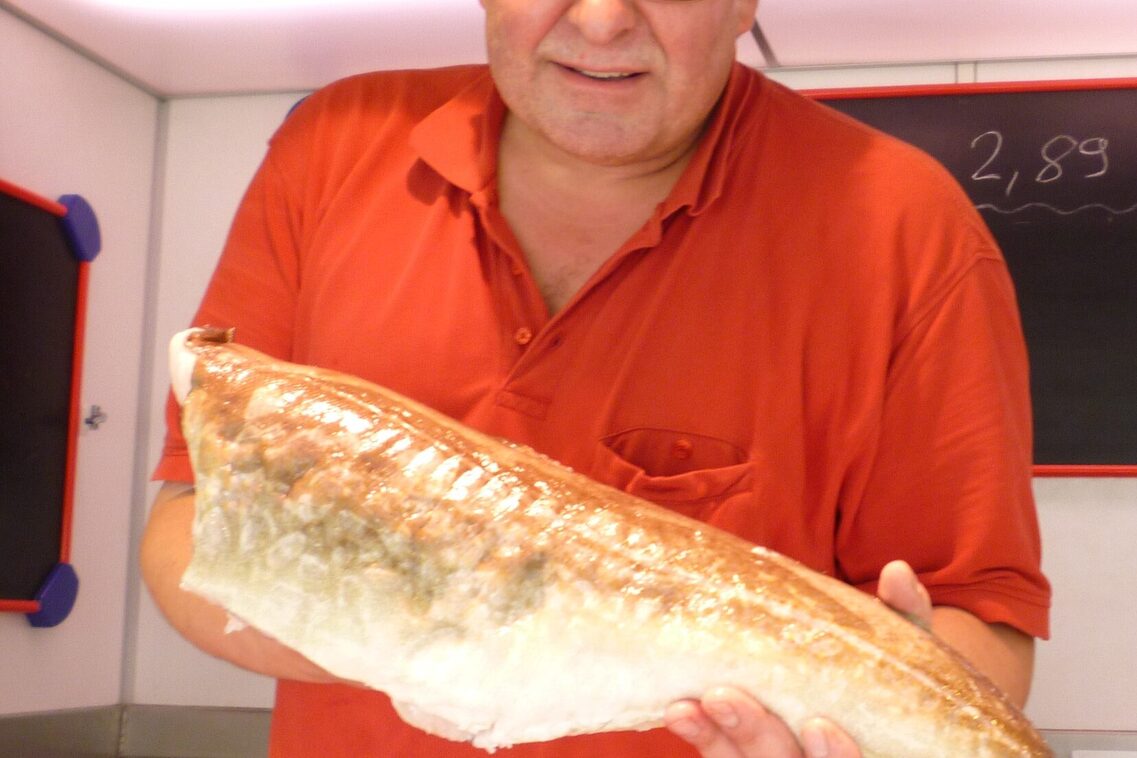 Verkäufer hält Fisch in die Kamera