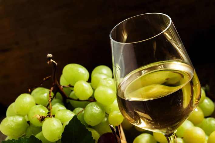 Gefülltes Weinglas im Weintrauben im Hintergrund