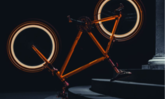 Fahrrad dass im Dunkeln auf Sattel und Lenker steht mit orangem Gestell un