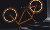 Ein auf dem Kopf stehendes orangenes Fahrrad vor dunklem Hintergrund mit l