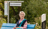 Frau sitzt auf Mitfahrer-Wartebank