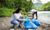 Junge Menschen sammeln Müll am Flussufer