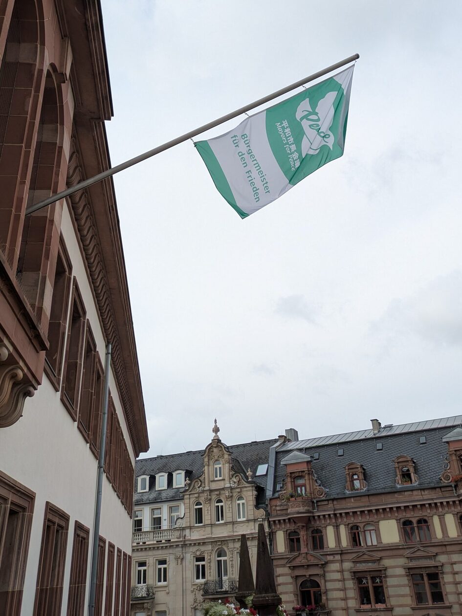 Auf dem Foto ist die weiß-grüne Flagge des Bündnisses "Mayors for Peace" am Wiesbadener Rathaus zu sehen.