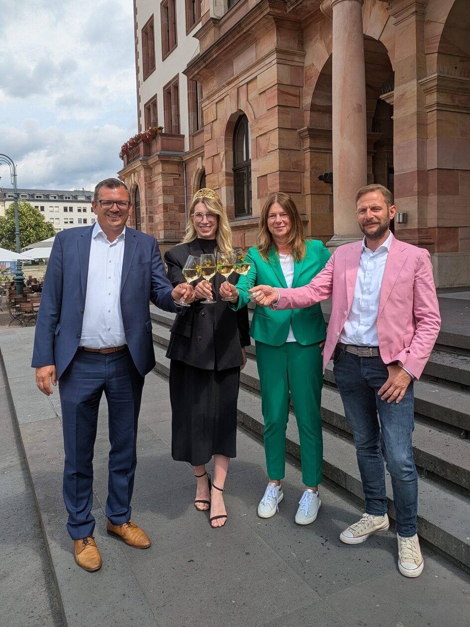 Simon Rottloff, Prokurist WICM GmbH, Lena Orth, Rheingauer Weinkönigin, Bürgermeisterin Christiane Hinninger und Dominik Russler, Geschäftsführer Rheingauer Weinbau-verband e. V. und Rheingauer Weinwerbung GmbH auf der Rathaustreppe mit befüllten Weingläsern in der Hand