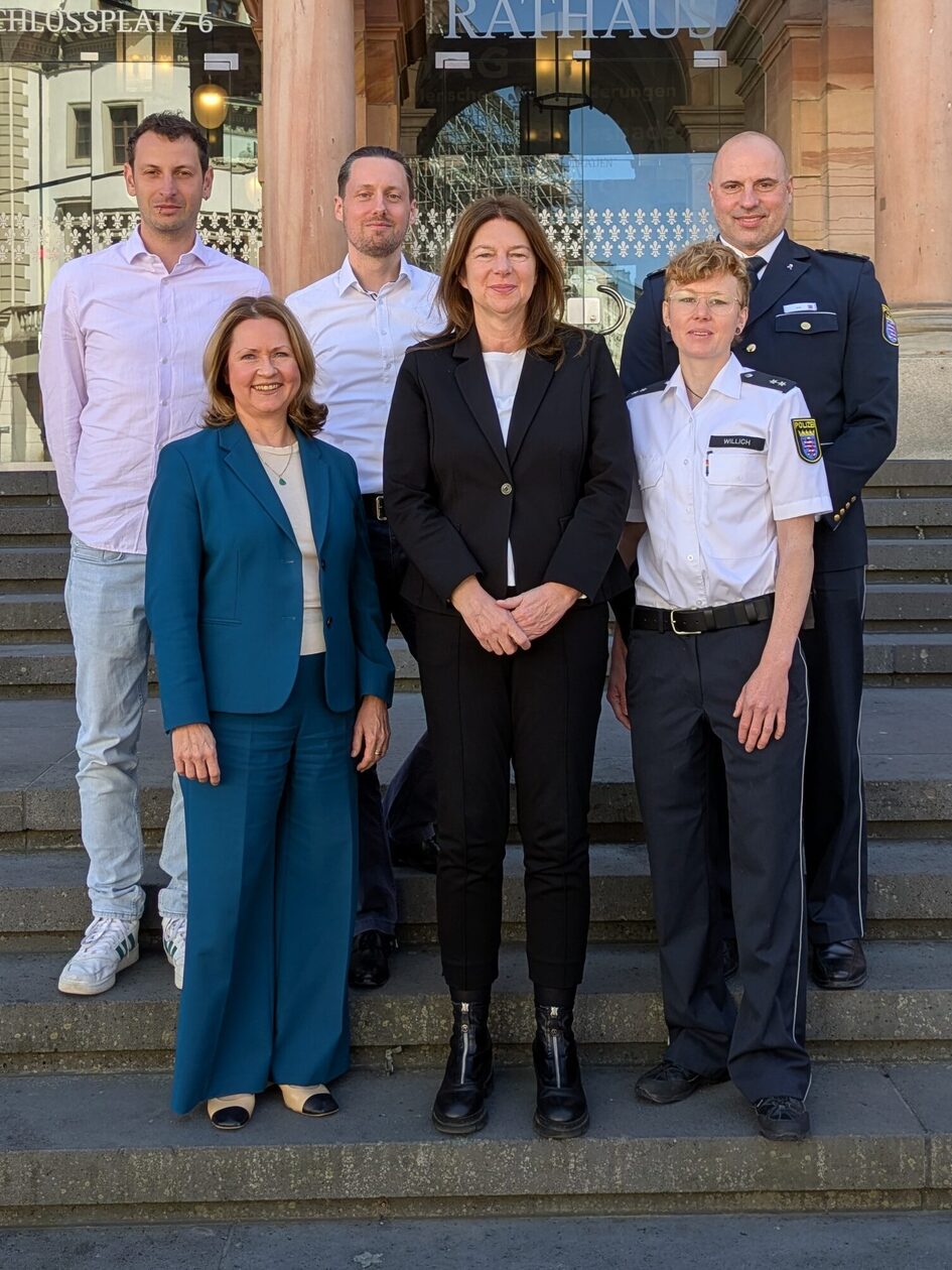 Auf dem Foto sind sechs stehende Personen auf der Freitreppe vor dem Wiesbadener Rathaus zu sehen.