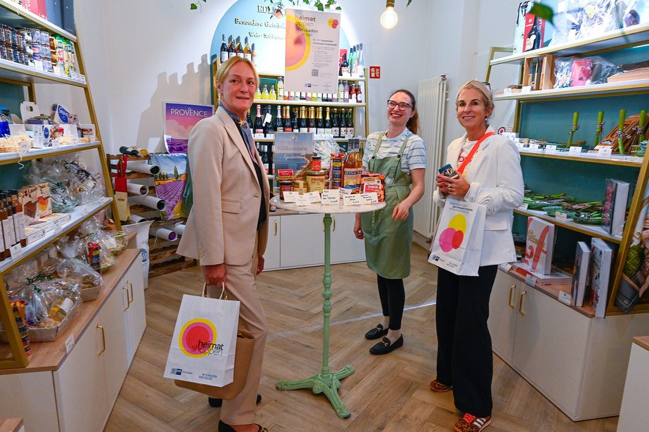 „heimat shoppen“-Rundgang in der Wiesbadener Innenstadt: Daniela Georgi, Wirtschaftsdezernentin (rechts), und Sabine Meder, Hauptgeschäftsführerin der IHK Wiesbaden (l.), besuchen das Geschäft „Chez Madlen“ in der Neugasse. Inhaberin Marie Bockstaller berichtet über die Aktionen ihres Bistros und Feinkostladens.