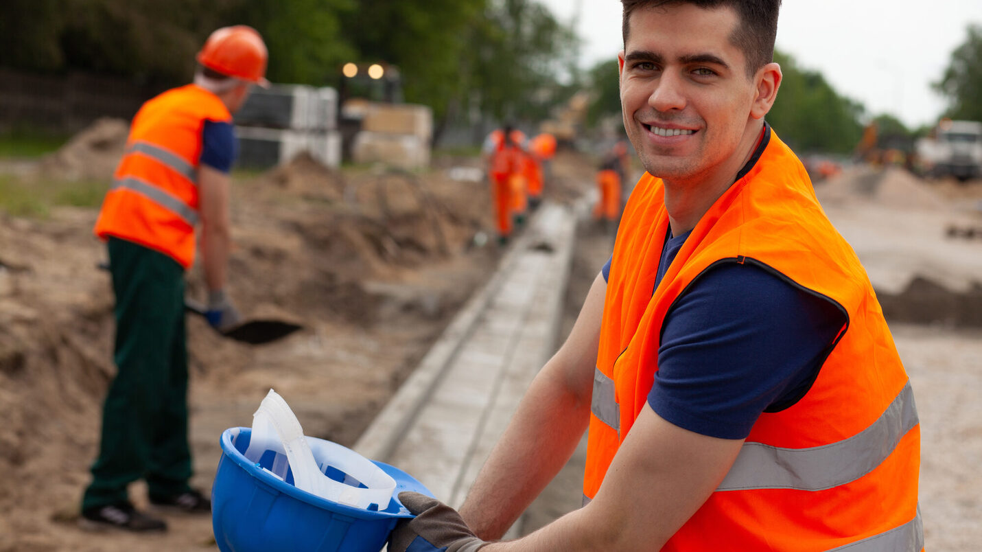 Handsome young road construction worker in orange safety jacket