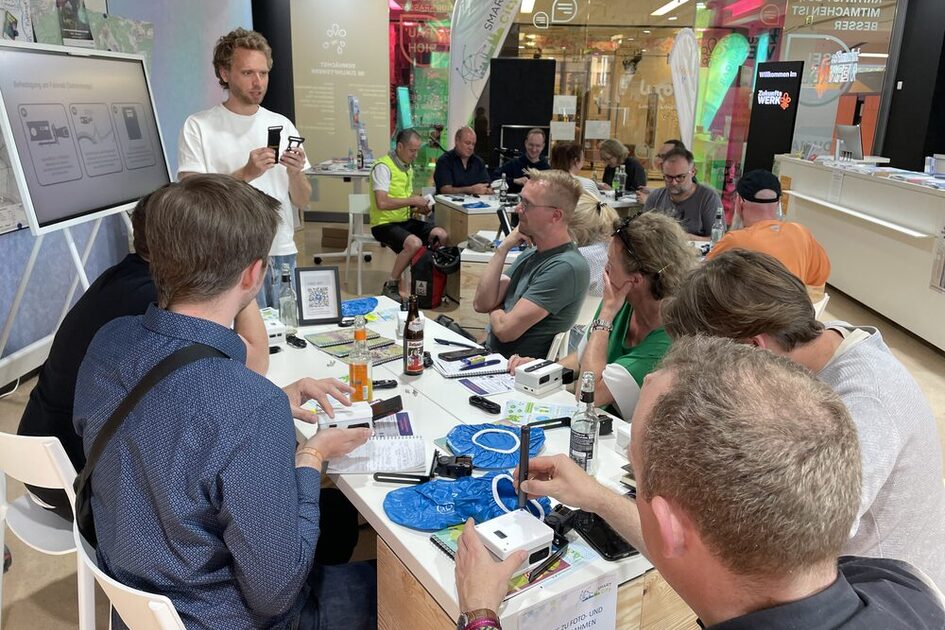 Teilnehmende des Sensor-Workshops um einen Tisch gruppiert, während der Referent die Sensoren erklärt.