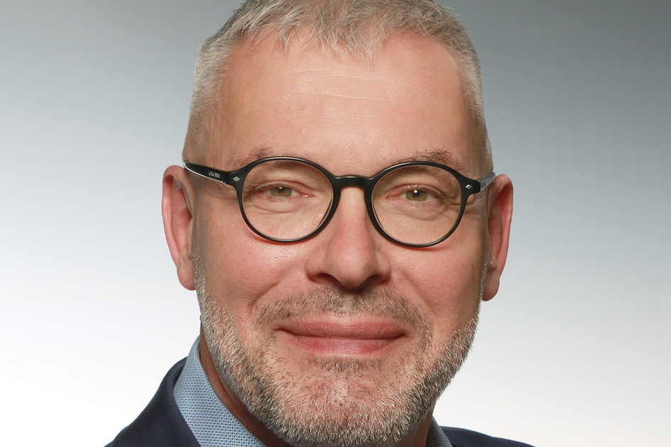 Mann mit kurzen Haaren, Bart und Brille mit Hemd und Jacket.