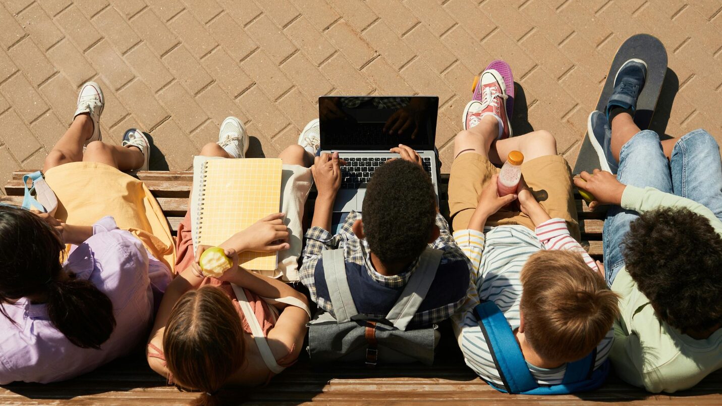 Schülerinnen und Schüler sitzen auf einer Bank