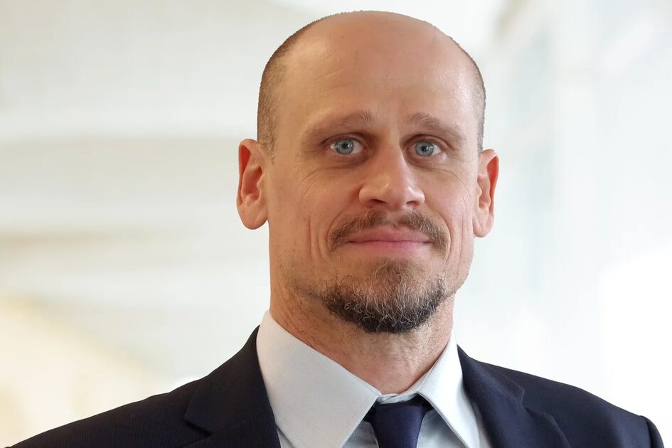 Mann mit kurzen Haaren, Bart und Anzug.